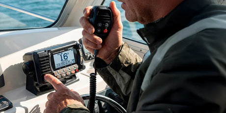 Boater using a VHF marine radio at the helm.