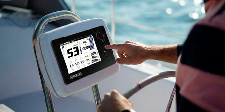 An overhead view shows a person with a pink and blue striped shirt and a watch on their left wrist, touching the black Yamaha digital display on a white console