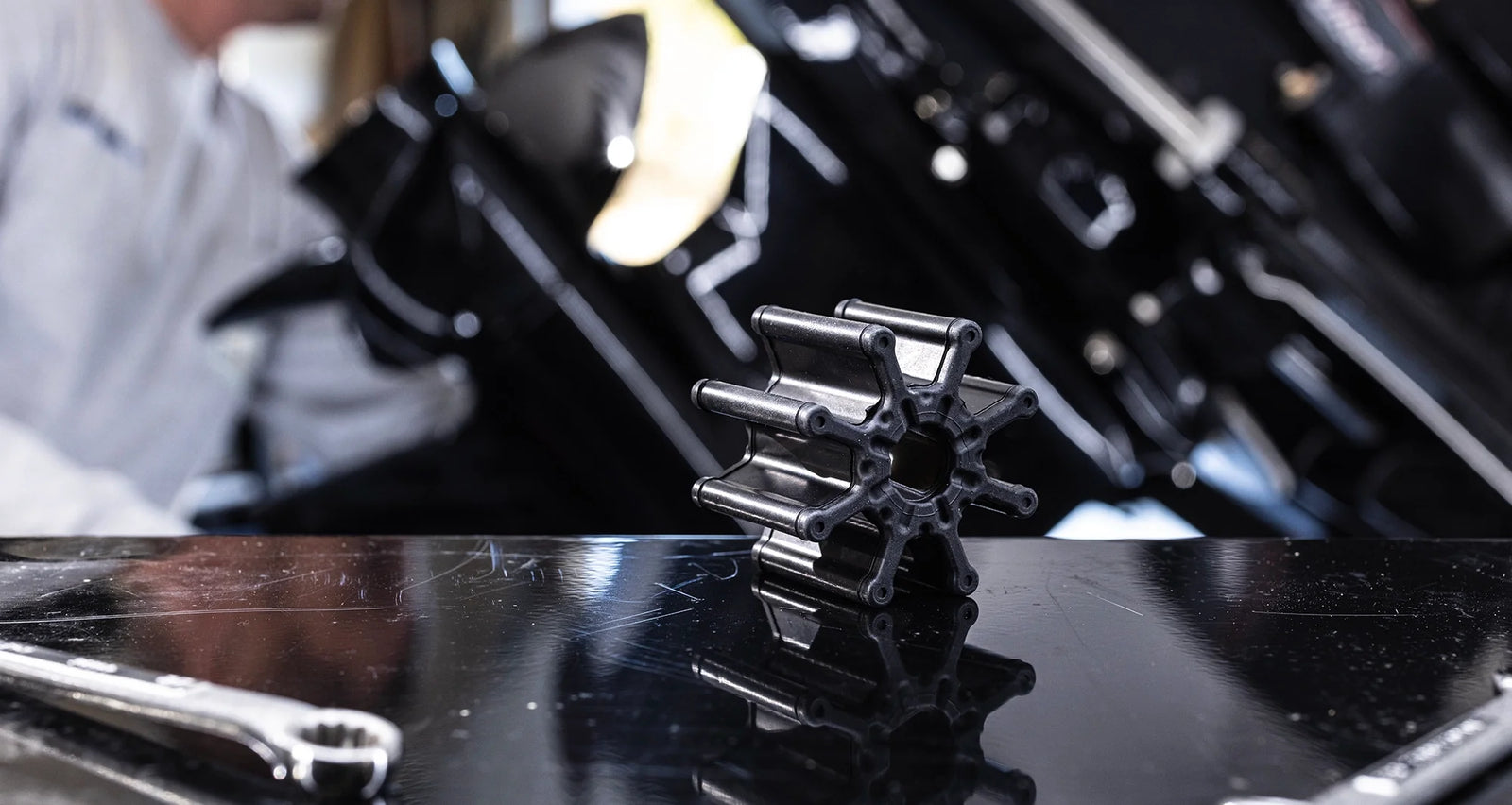Close-up of a Mercury outboard engine impeller on a black workbench with tools