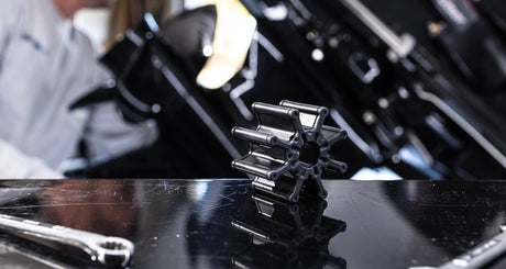 Close-up of a Mercury outboard engine impeller on a black workbench with tools